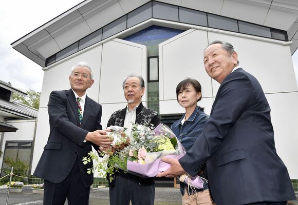 １００万人目の入館者となった高久さん（左から２人目）に花束を贈る広田町長（右）ら