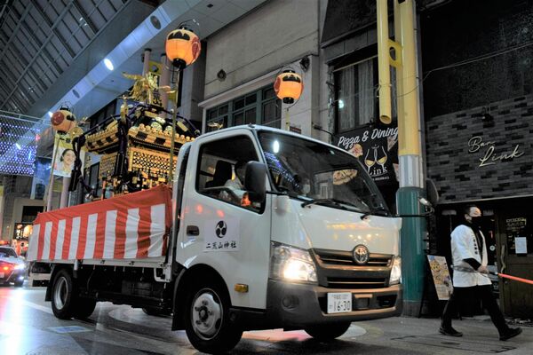 トラックでオリオン通りを渡御する神輿