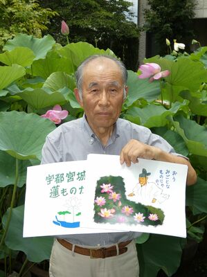 紙芝居を紹介する印南さん。背後のハスの花は発掘された１４９０年代の実が発芽し、開花したもの