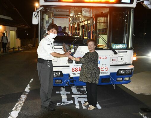 最後の運転手になった安部主任運転士（左）に花束を手渡す佐藤さん