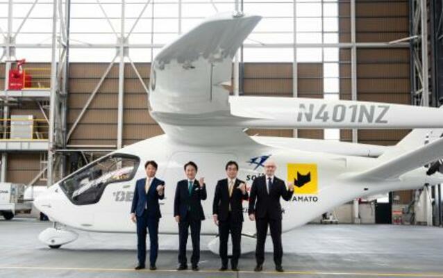 　電動航空機の前でポーズをとる北九州市の武内和久市長（左から２人目）ら＝１７日午前、北九州空港（北九州市提供）