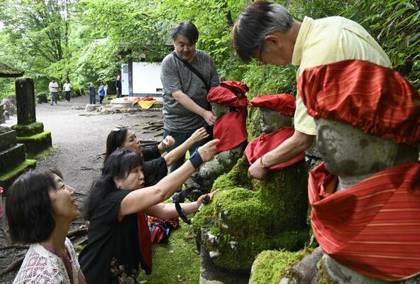 地蔵に帽子や前掛けを着せるメンバー