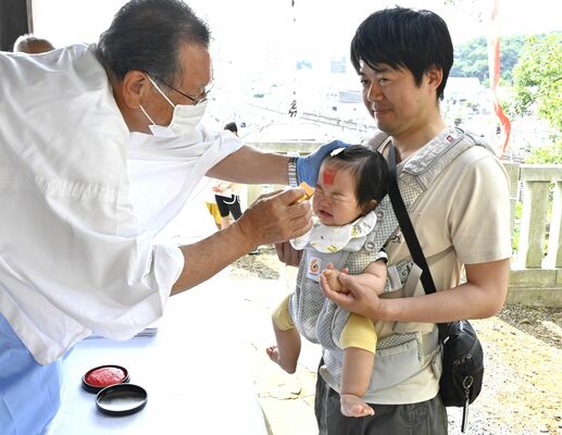 ペタンコ祭りで額に朱印を押してもらう赤ちゃん