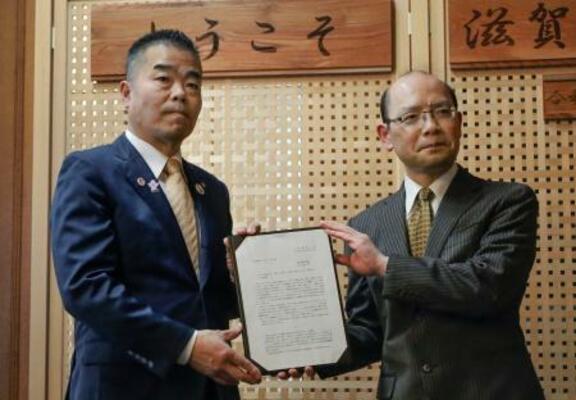 滋賀県税制審議会から中間答申を受け取る三日月大造知事(左)=4日午後、滋賀県庁