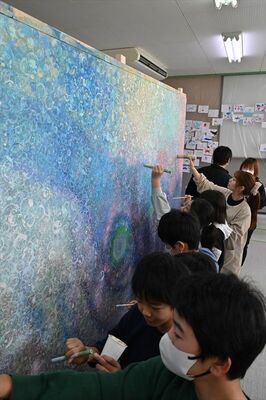 ｕｍｉ．さん（奥から３人目）と点描画を制作する児童