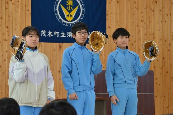 グラブを受け取り、お披露目する代表の児童ら