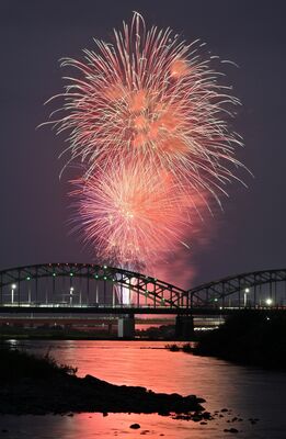 中橋の上空に上がり、渡良瀬川の水面にも写り込む花火＝３日午後７時20分、足利市通４丁目