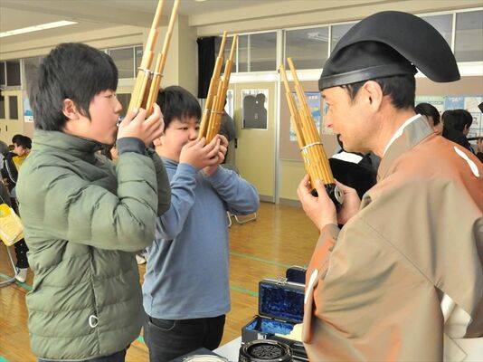 手ほどきを受け、雅楽の楽器の音を出す児童たち