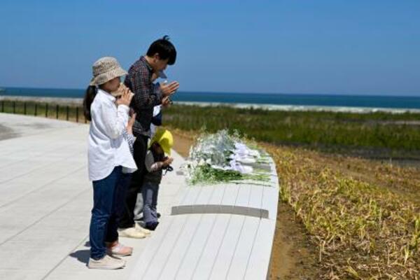 　福島県復興祈念公園で献花し、手を合わせる家族＝２日午後