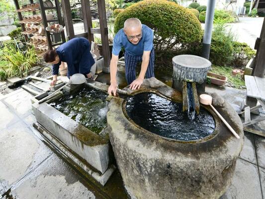 つきぬき井戸の手水舎を手入れする黒羽夫妻