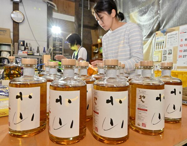 初の県産ウイスキー「哲」のラベル貼り作業＝７日午前11時、小山市粟宮
