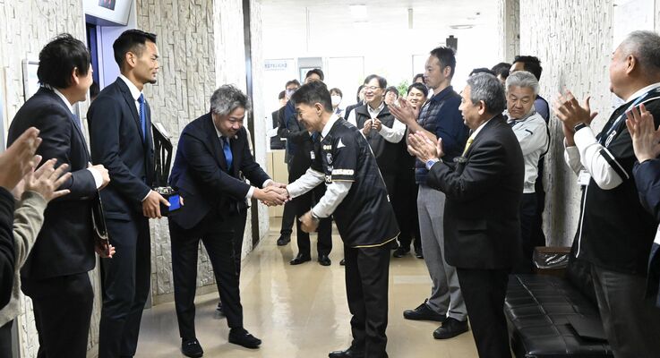 市職員が拍手で出迎える中、大栗社長（左から３人目）と握手する早川市長（同４人目）