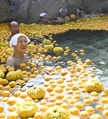 一面にユズが浮かぶ露天風呂を楽しむ温泉客