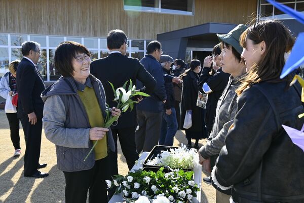 東日本大震災後、初めて「３月11日」を古里で迎え、知人と談笑する武内さん（左）＝11日午後３時、福島県大熊町