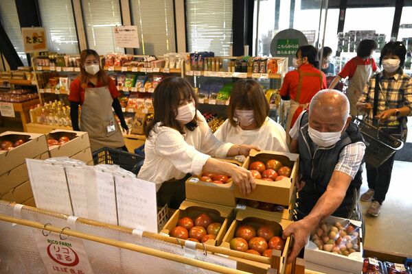 開店直後にトマトを買い求める客たち