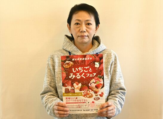 「いちごとみるくフェア」のチラシを持つ臼井さん