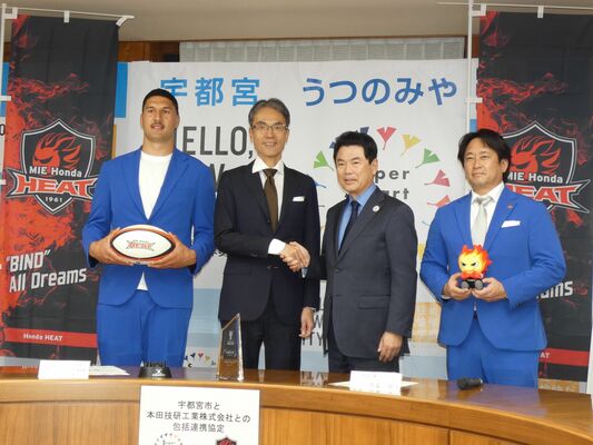 協定を結び、握手を交わす佐藤市長（中央右）と小澤常務（同左）。選手やＧＭも駆け付けた＝４日午後３時、宇都宮市役所