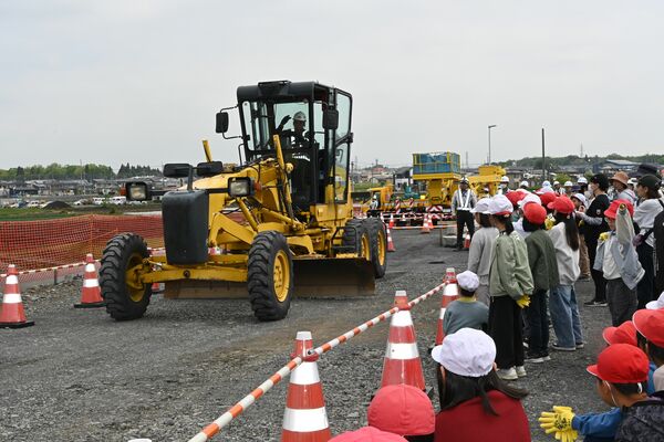 路面を整地する作業車を見学する石橋北小の児童ら