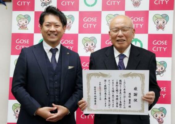 奈良県御所市役所で山田秀士市長(左)から感謝状を受け取った西辺豊彦さん=12日午後