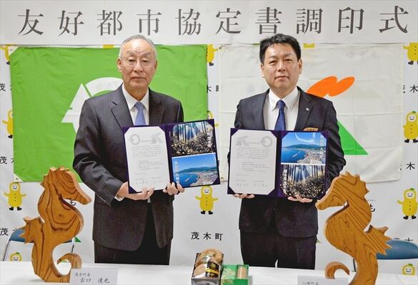 友好都市協定書を掲げる堀内町長（右）と古口町長