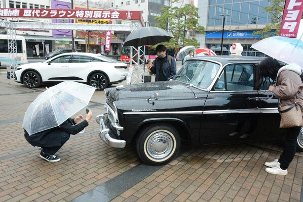 初代クラウン（手前）や新型（奥）を見て回る来場者たち＝２６日午前、宇都宮市馬場通り４丁目