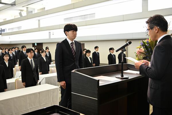 内定通知書を読み上げる斎藤人事部長（右）と、内定式に臨んだ学生ら＝１日午前、宇都宮市