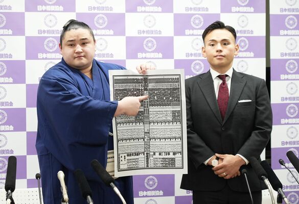 新入幕を果たし、番付表に記された自らのしこ名を指さす若ノ勝（左）と師匠の湊川親方＝27日午後11時40分、両国国技館、橋本裕太撮影