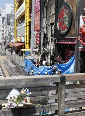 　大阪・道頓堀のビル火災で行われた現場検証。現場近くには花束などが供えられていた＝１９日