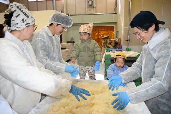 蒸し米をほぐしながらひっくり返して冷ます放冷作業に挑む参加親子＝１月１１日、鹿沼市上粕尾