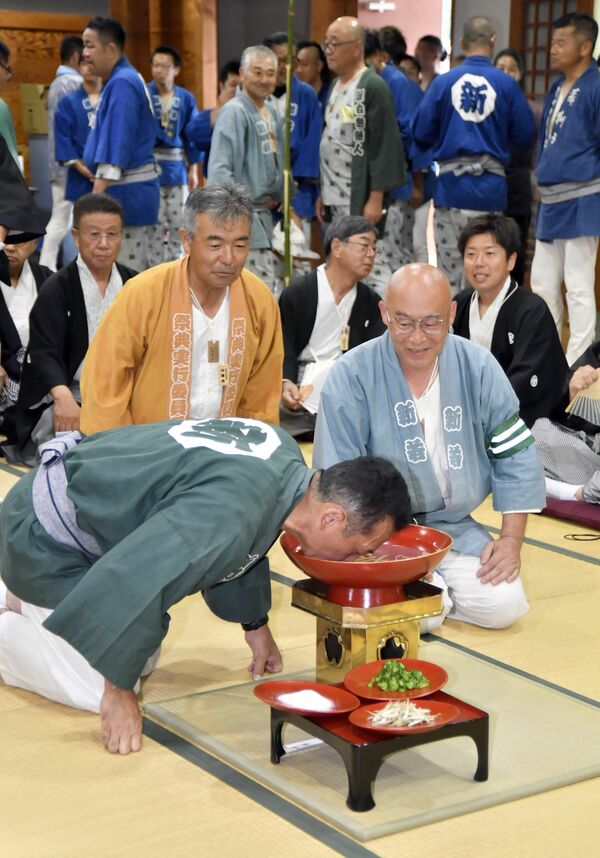 大杯に注がれた燗酒を飲み回す男衆＝24日午後１時20分、益子町益子