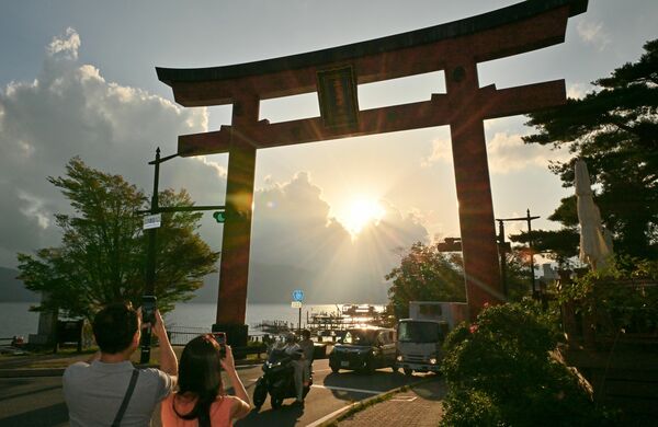 大鳥居の奥に沈む夕日＝16日午後４時55分、日光市中宮祠
