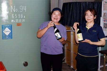 　松波酒造の日本酒を手にする金七聖子さん（左）＝２０２５年８月、石川県小松市