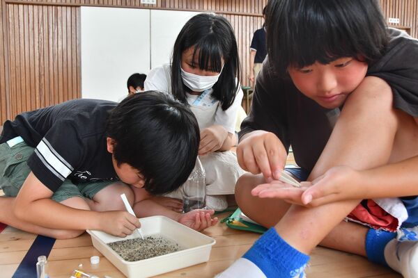 砂の中からマイクロプラスチックを探す児童