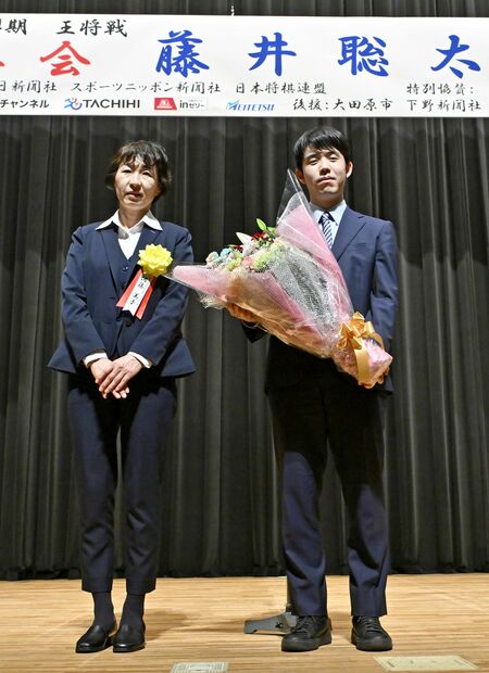 祝勝会で花束を受け取り記念撮影に応じる藤井王将（右）＝28日午後６時20分、大田原市本町１丁目