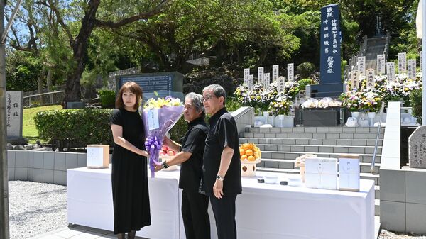 栃木市の関係者からの寄付で準備した花束を島守の塔に手向ける栃の葉会の３人＝23日午前11時30分、沖縄県糸満市摩文仁