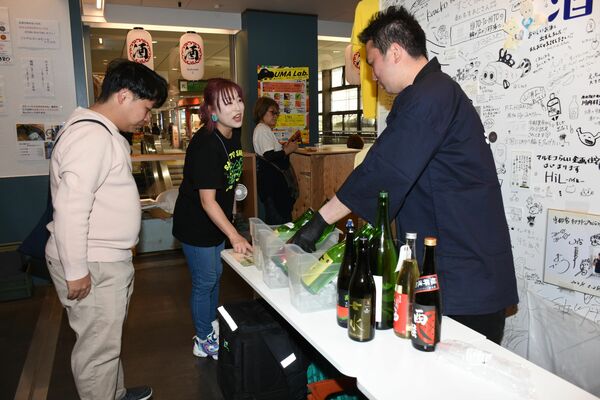 宇都宮パセオのスタンドバー「ＳＡＫＥ＿ＴＯ＿ＳＡＫＥ」で日本酒イベント出店者に声を掛ける星絵理子さん（中央）＝４月２５日