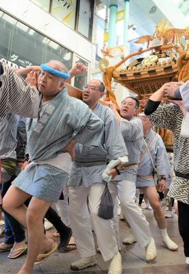 威勢良くオリオン通りを渡御する市場神輿
