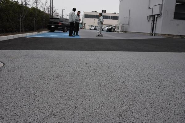 駐車場に敷かれている遮熱性舗装。通常の舗装(奥の色が濃い部分)に比べ、路面温度上昇を抑えるという=1月下旬、下野市柴のニチレキ技術研究所