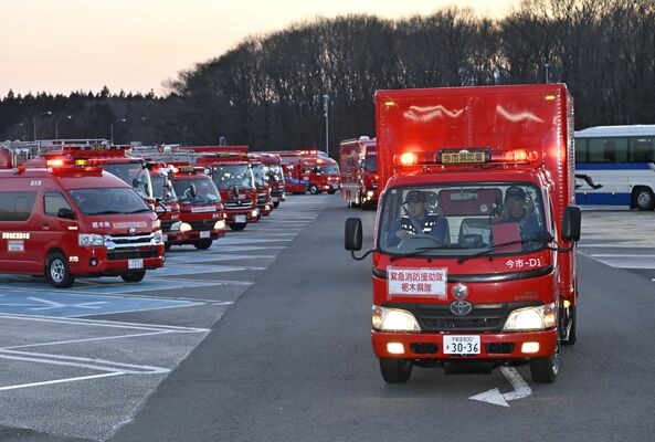東北道那須高原サービスエリアに集合し、岩手県へ出発する県内各地区の消防車両＝27日午後５時30分、那須町豊原丙