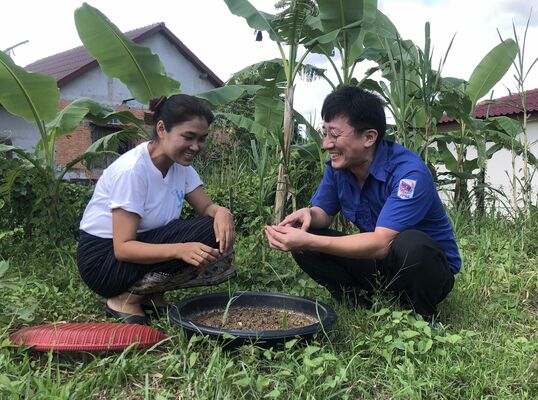 昆虫養殖について住民と話し合いをする石塚さん（右）＝８月上旬、カムアン県