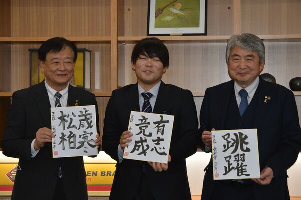 市に贈った色紙を手に、笑顔を見せる長谷部五段（中央）