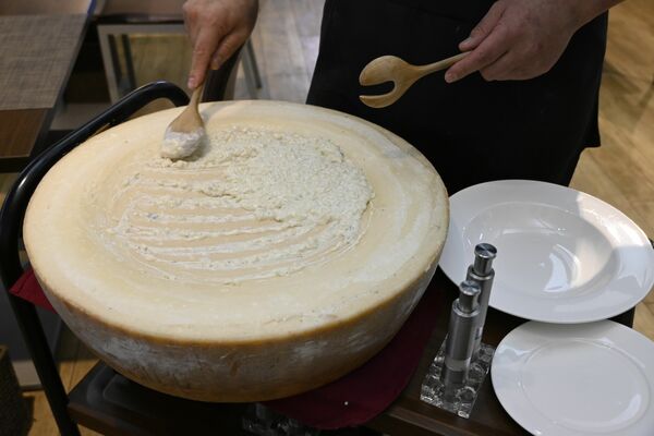 パルミジャーノ・レッジャーノの器の中でリゾットを混ぜる