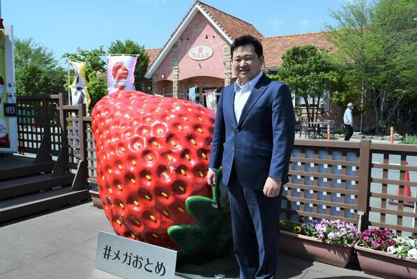 観光農園に設置されているイチゴのオブジェと小黒社長＝小山市