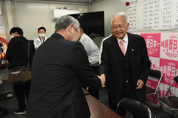 当選確実となり佐藤勉衆院議員と（手前）と握手する板橋一好氏＝９日午後11時40分、小山市立木