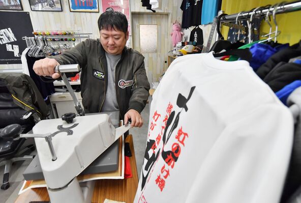 プレス機でプリントＴシャツを製作する池守さん。「足尾を盛り上げたい」と過疎の進む生まれ故郷で起業した＝２月中旬、日光市足尾町松