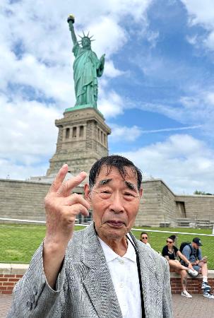 　自由の女神像の前に立つ北三郎さん（仮名）＝６月、米ニューヨーク（支援者提供）