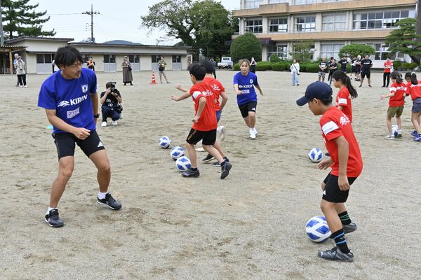 サッカーで児童と交流する松井さん（左）と岩渕さん（中央）