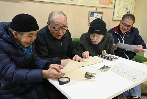 投稿された写真などを見て懐かしむ左から簗嶋さん、大塚さん、大橋さん、増渕さん