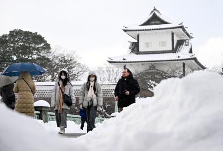 　雪が降り積もる中、金沢市内を歩く人たち＝２２日午後
