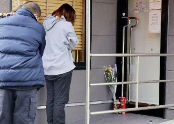 　現場となった店舗の出入り口に献花し、手を合わせる人＝昨年１２月、北九州市小倉南区